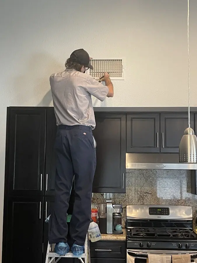 Technician inspecting an air vent during HVAC service in Glendale